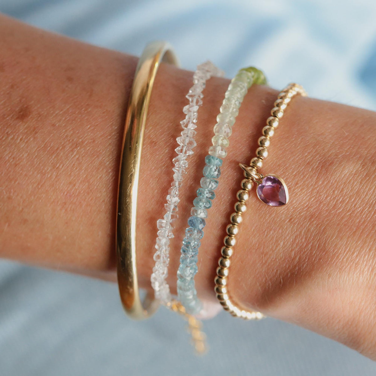 Gold filled bracelet featuring a 14K amethyst heart charm, designed by Earthly Abundance, with intricate gold detailing.