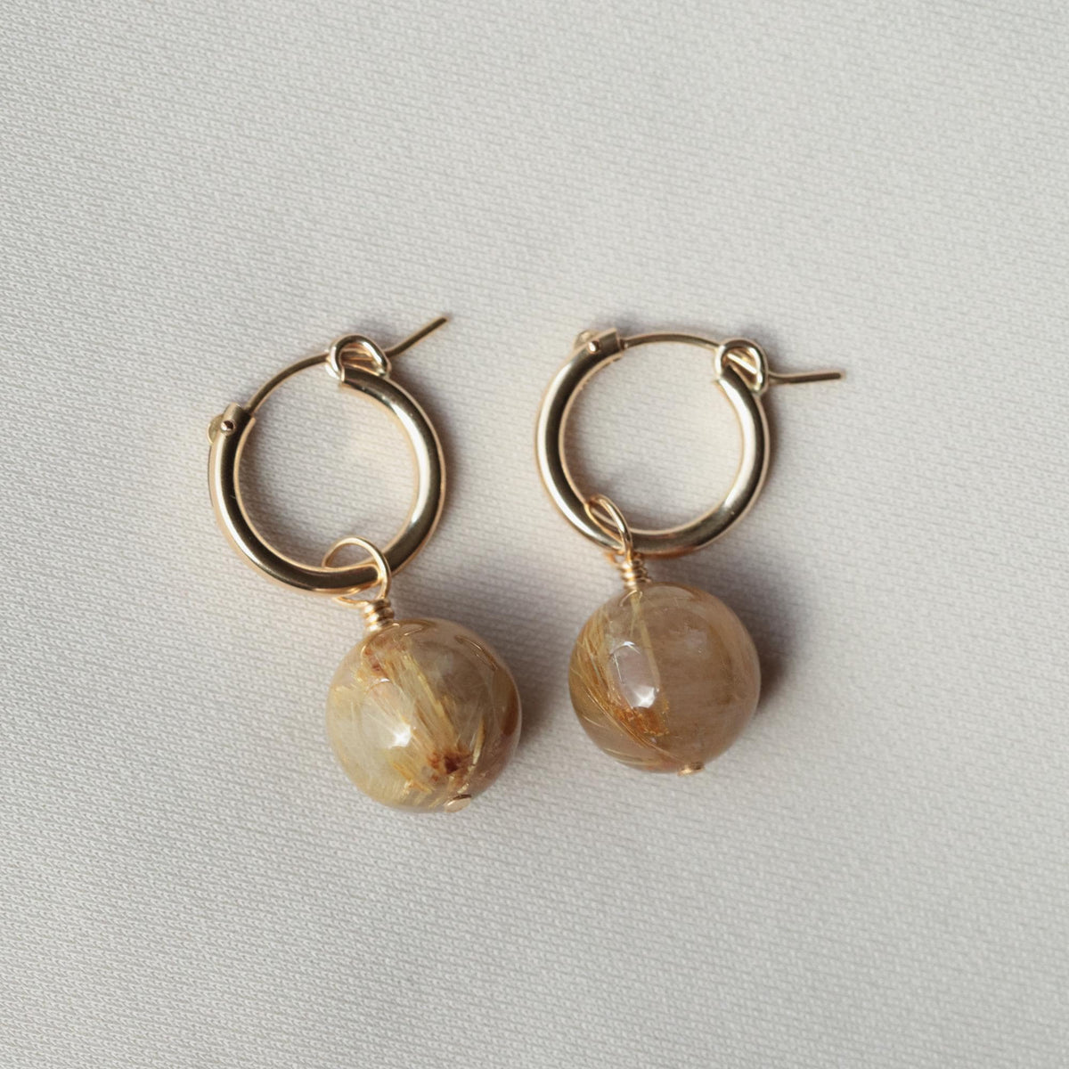 Golden rutilated quartz hoop earrings in 14K gold-filled setting, showcasing their sparkling stone and elegant hoop design.