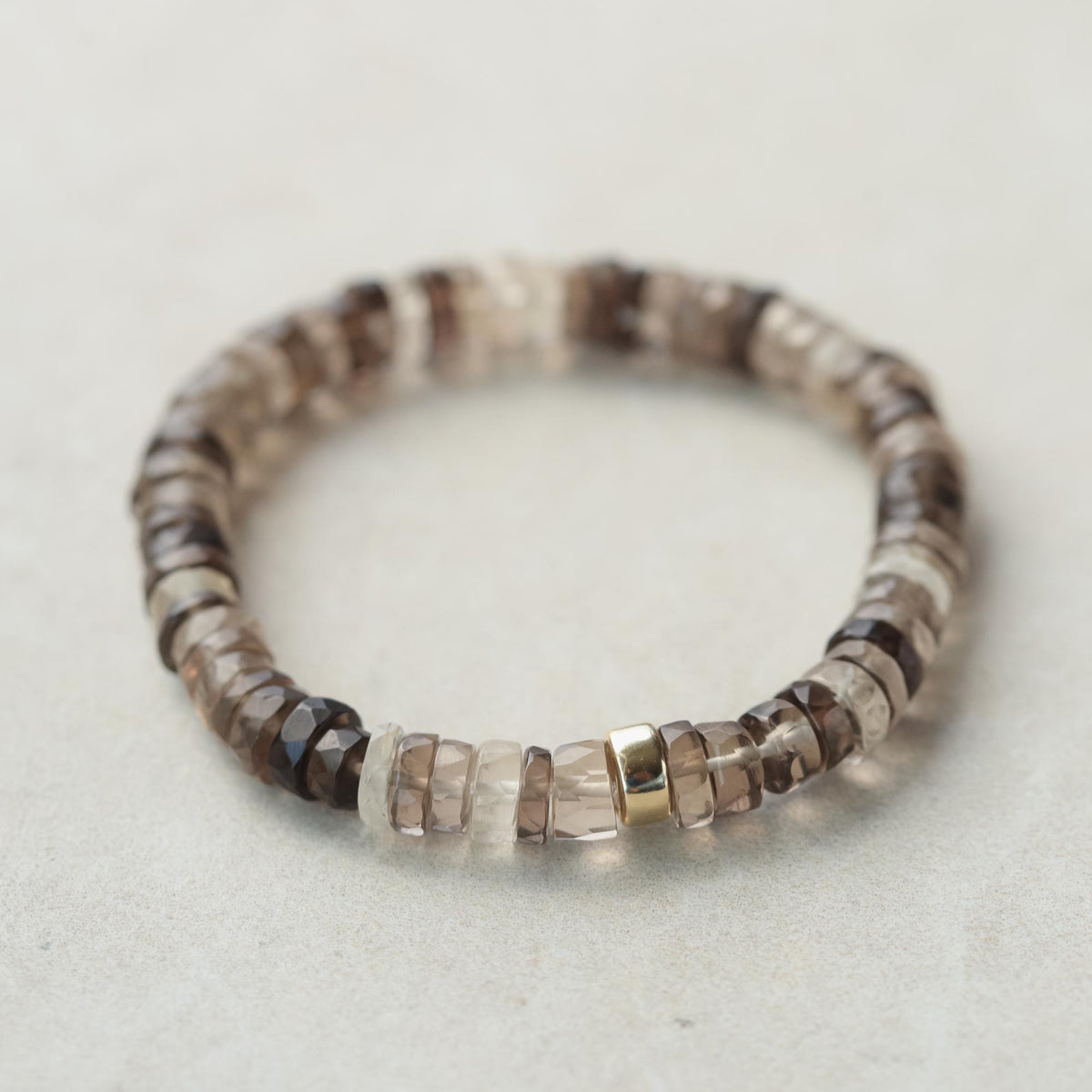 Smoky Quartz Heishi bracelet with small, round quartz beads on an elastic band, styled for casual wear.