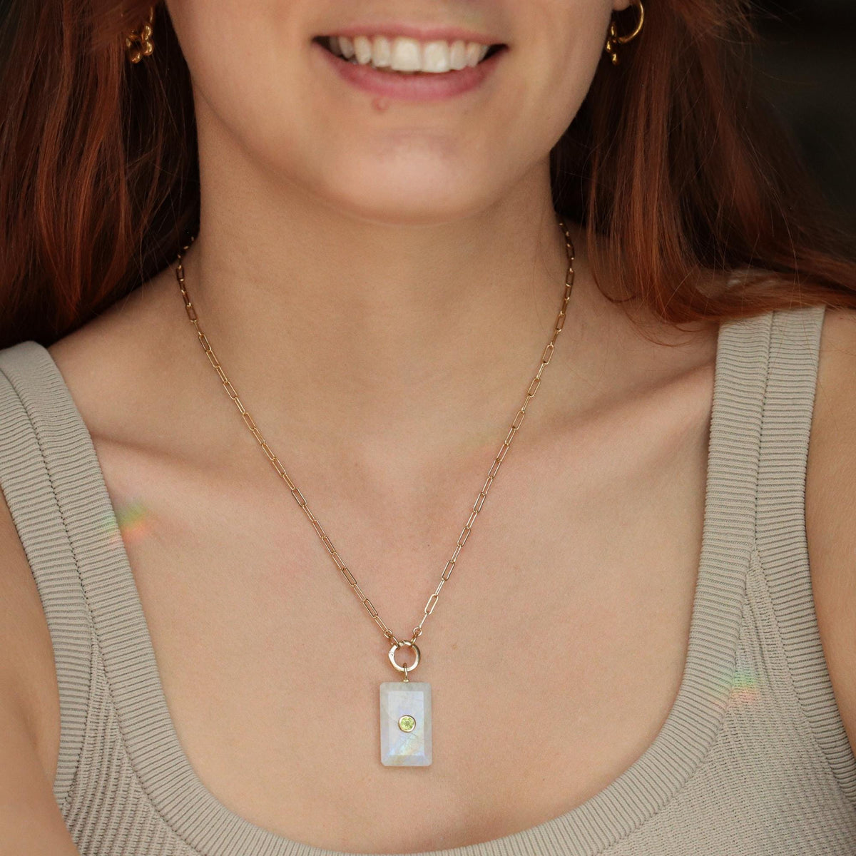 Earthly Abundance Moonlight Bar Moonstone pendant hanging on a chain, showcasing its luminous moonstone centerpiece.