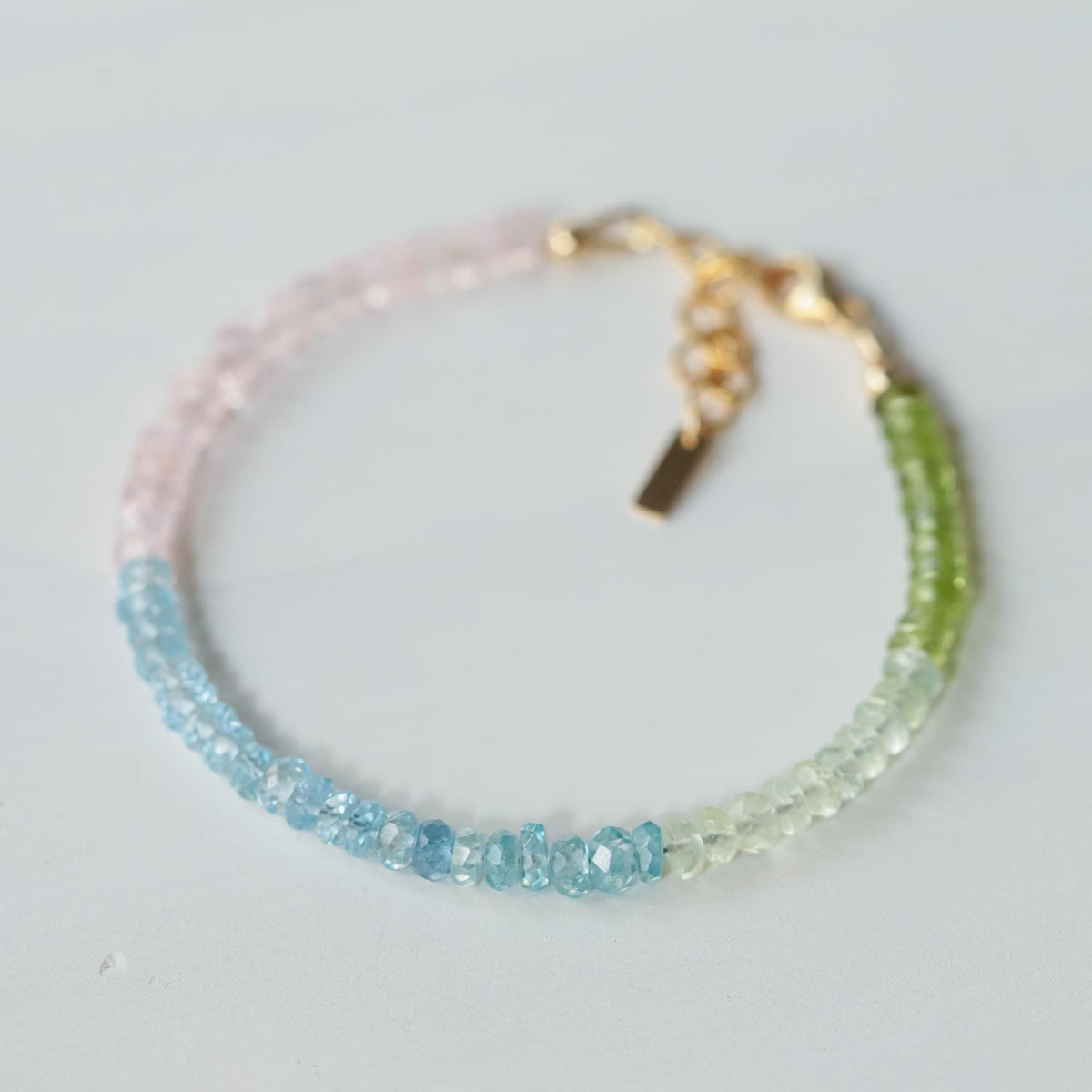 Assorted gemstones including peridot, prehnite, aquamarine, blue zircon, and morganite set in 14K gold filled jewelry.