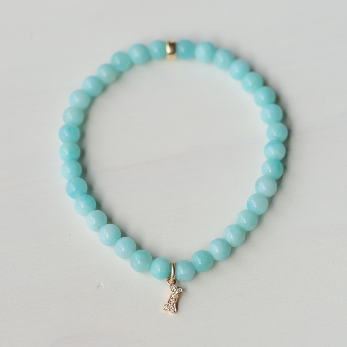 Diamond dog bone charm bracelet in 14K gold with a sparkling bone-shaped charm, featuring elegant craftsmanship.