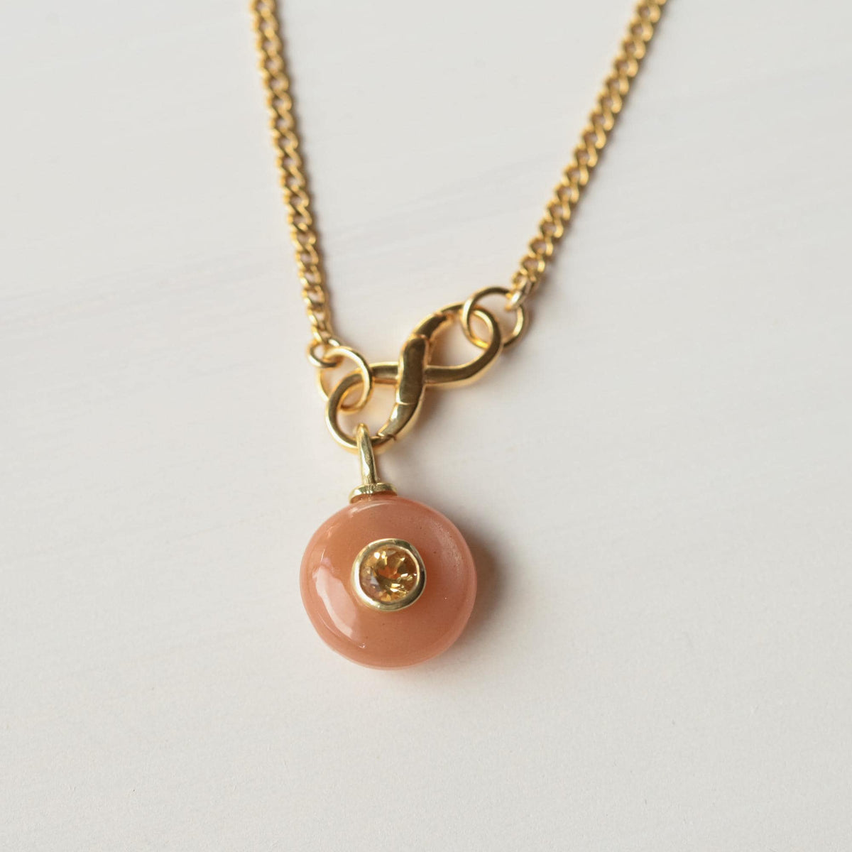 Infinity clasp curb chain necklace with peach moonstone and citrine, featuring a delicate gold chain and elegant gemstone accents.