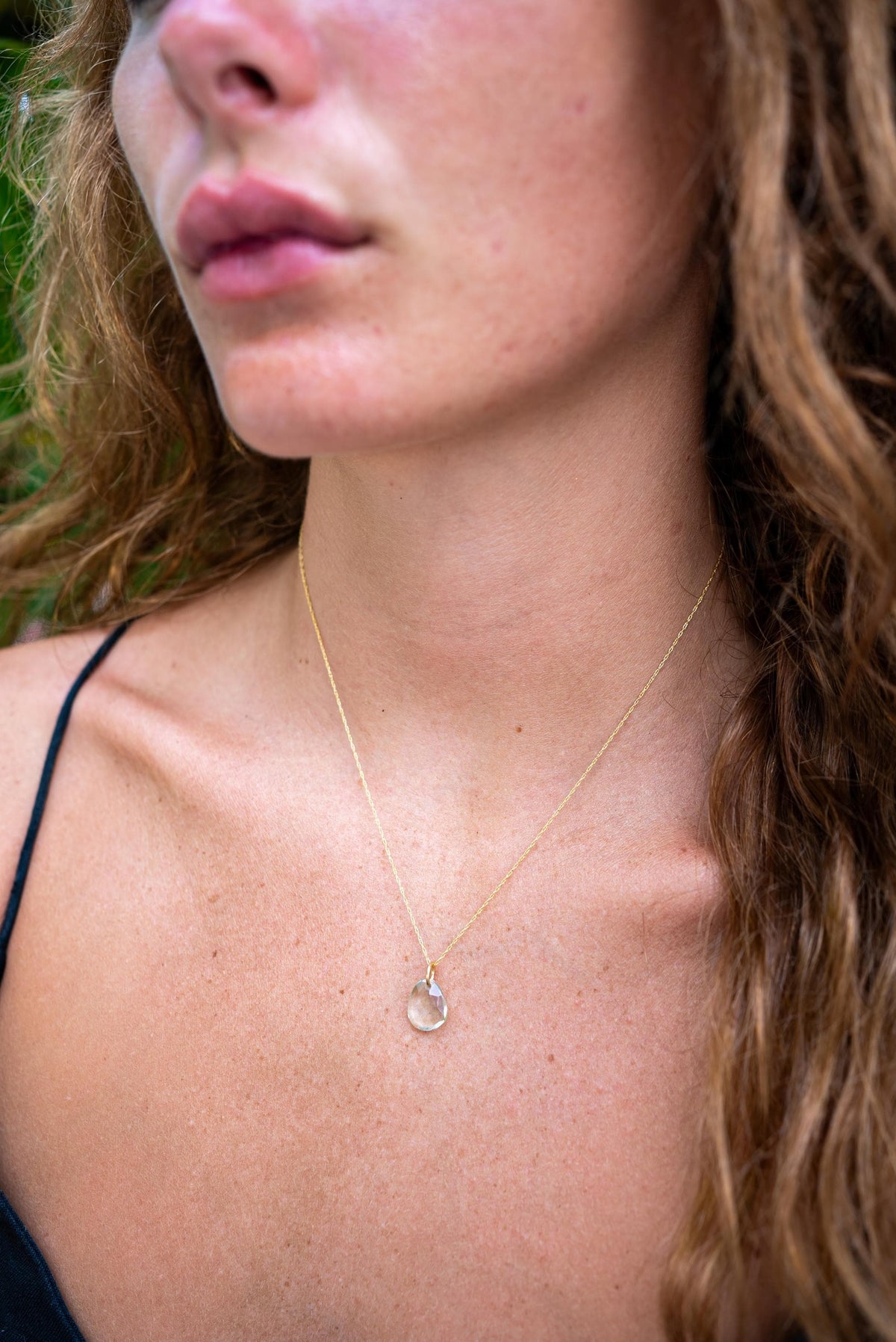 Green amethyst pendant in 14K gold setting, featuring a polished green gemstone with intricate gold detailing.