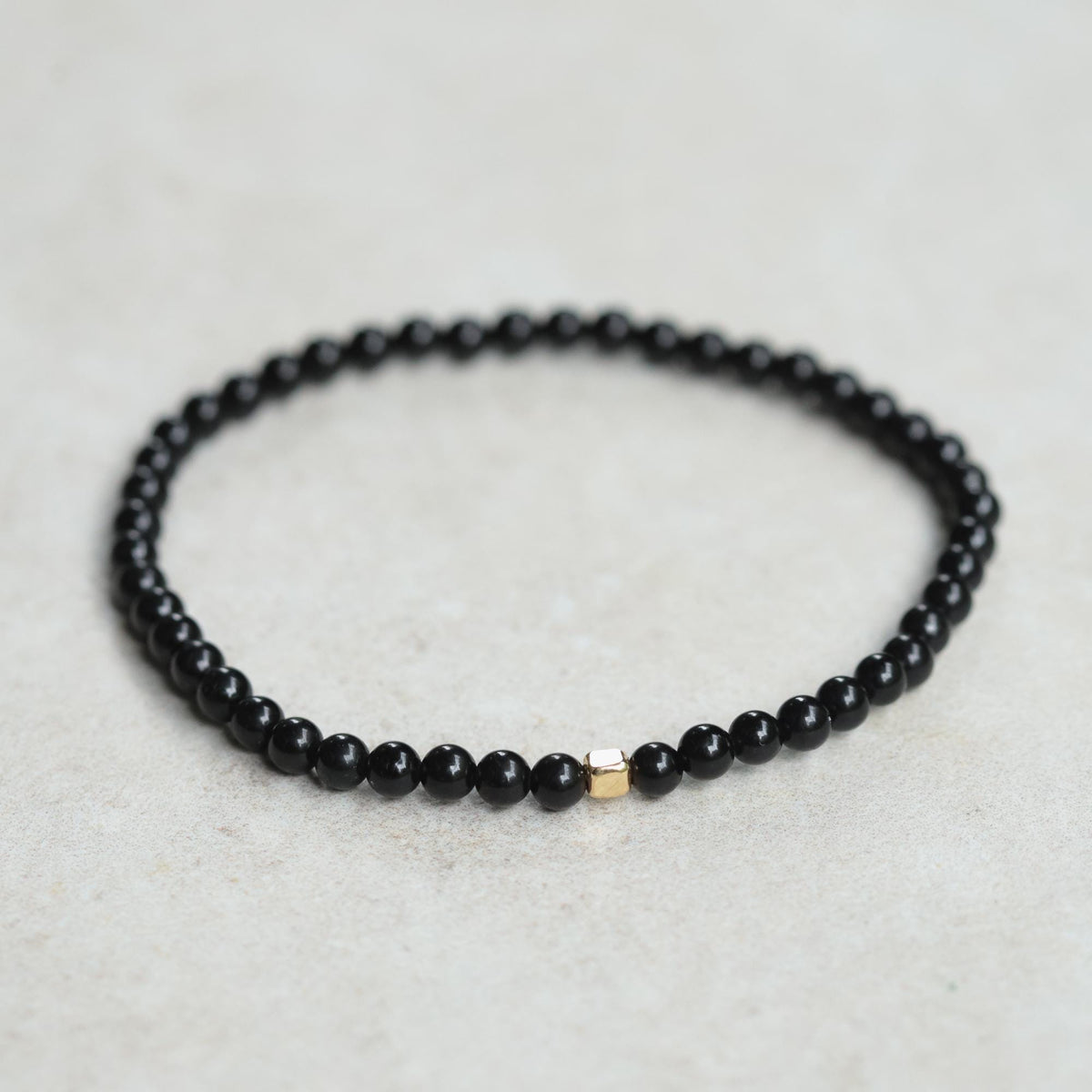 Men's black Tourmaline bracelet by Earthly Abundance featuring polished black stones on an elastic band.