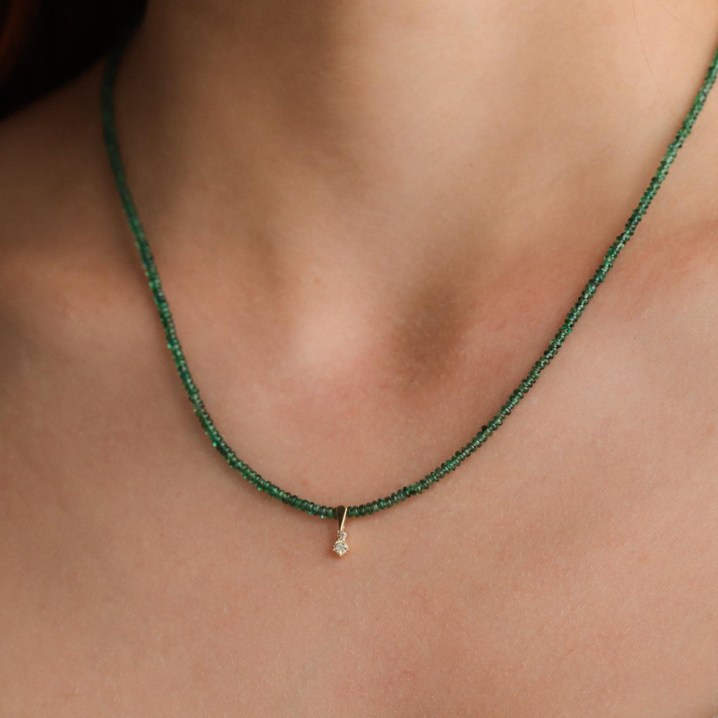 Zambian emerald and diamond necklace in 14K gold from Earthly Abundance, showcasing a vibrant green emerald pendant with sparkling diamonds.