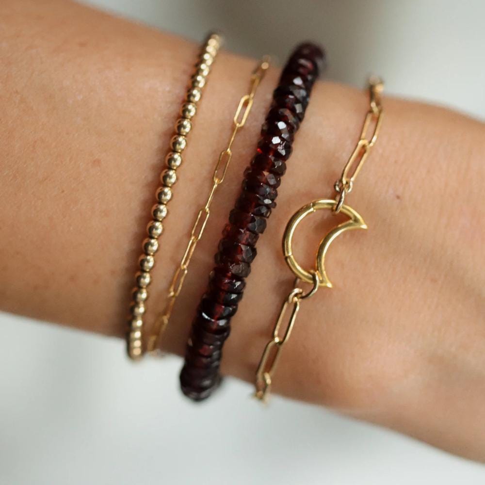 Earthly Abundance garnet heishi bracelet featuring small round red garnet beads strung together on an elastic band.