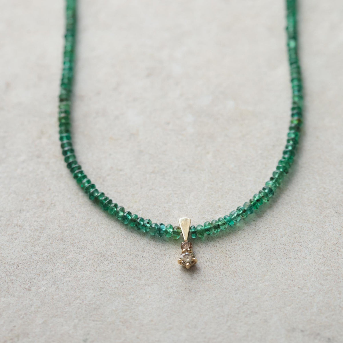 Zambian emerald diamond necklace in 14K gold featuring a vibrant green emerald pendant with sparkling diamonds.