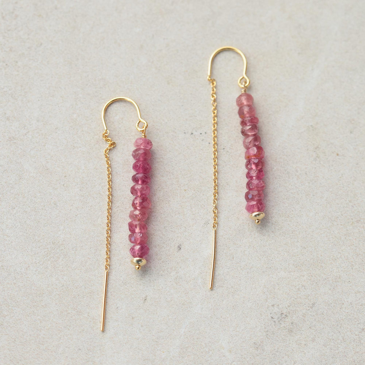 Pink tourmaline threader earrings with delicate gold chains, designed by Earthly Abundance, showcased against a neutral background.