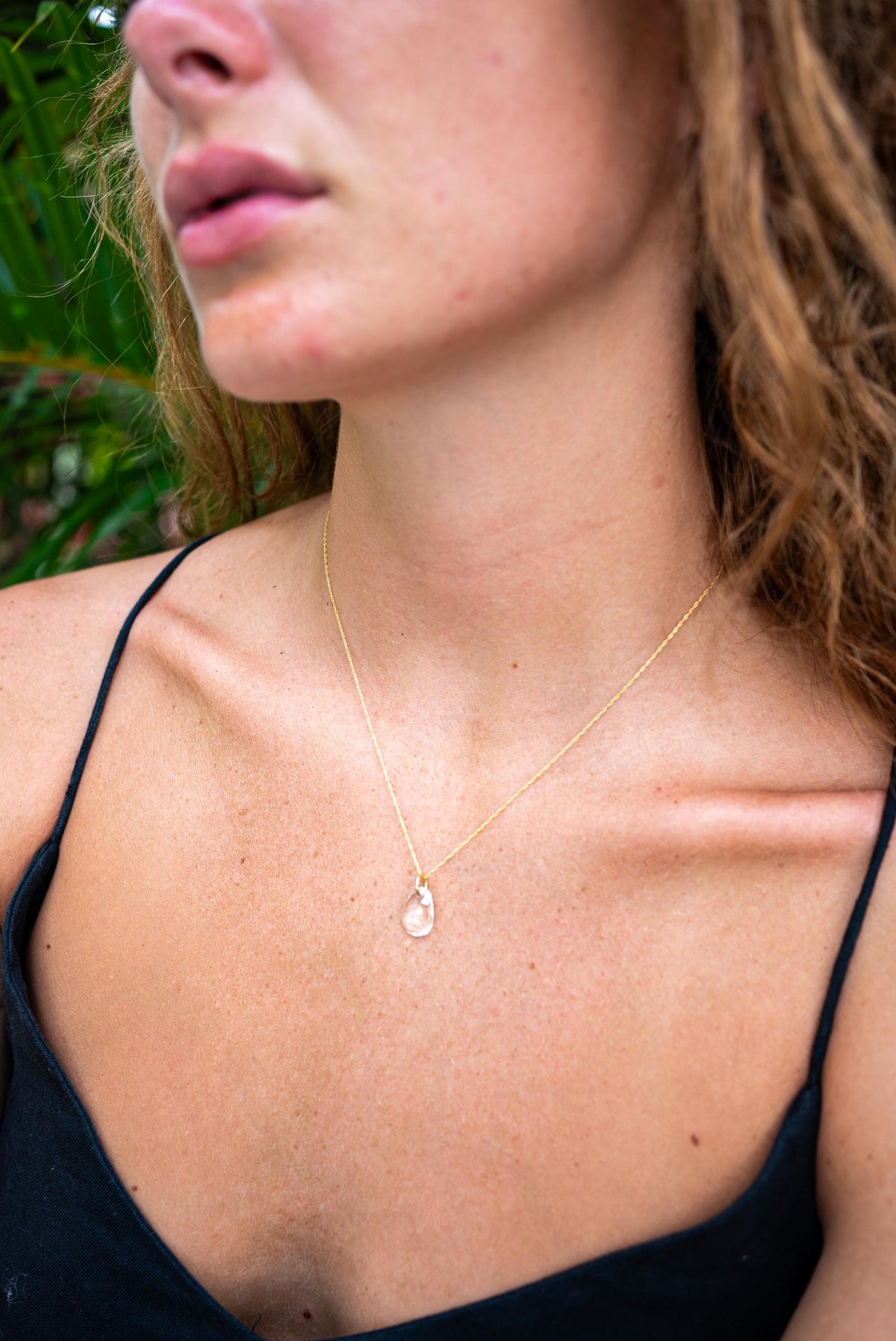 Clear quartz pendant necklace in 14K gold setting, featuring a polished crystal stone on a delicate chain.