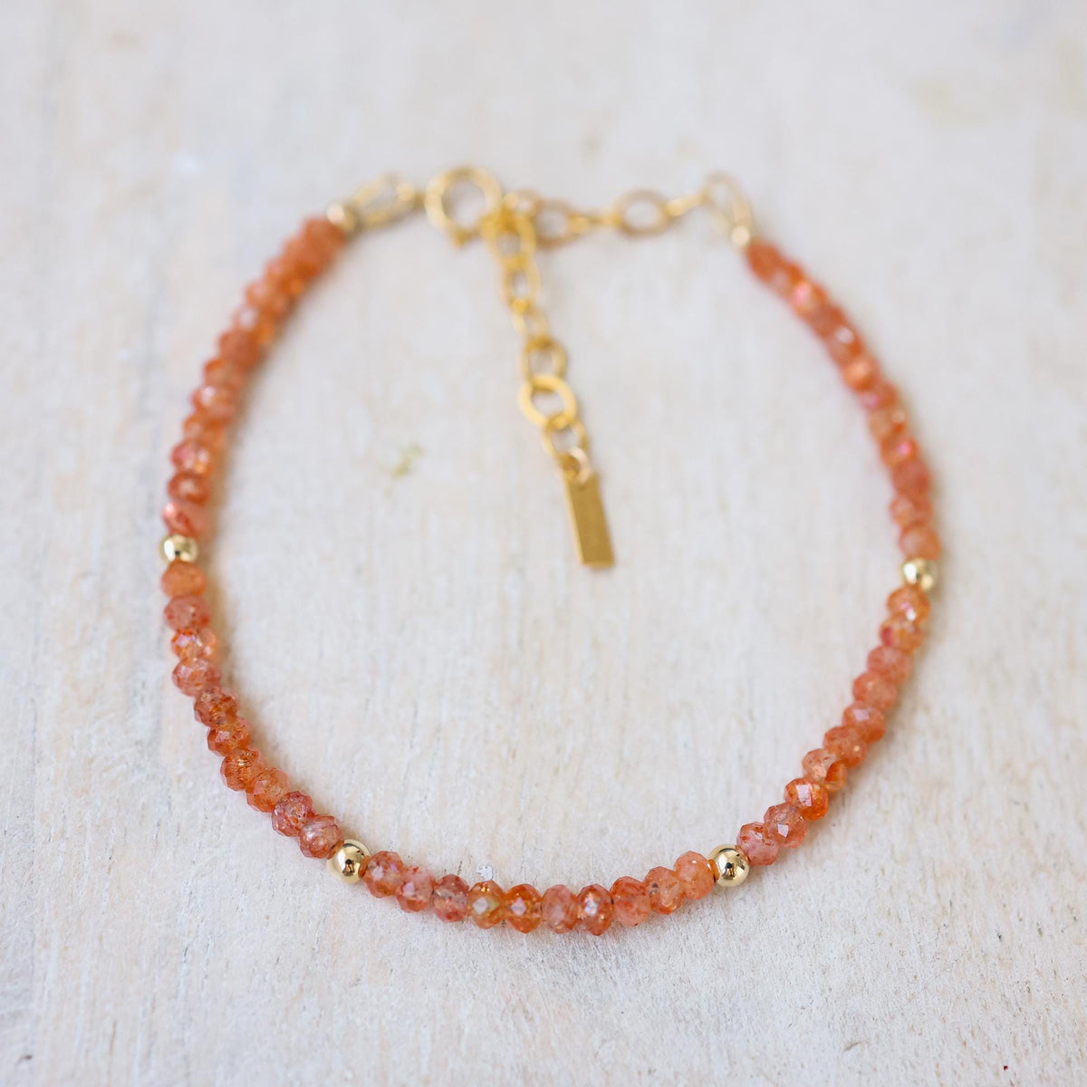 Sunset Crush Sunstone bracelet featuring orange and red sunstone beads on a stretch cord, by Earthly Abundance.