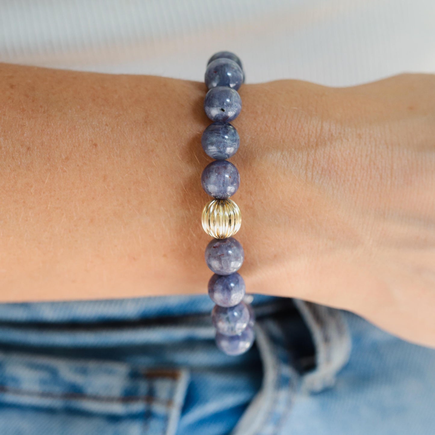 Iolite bracelet with 10mm beads from Earthly Abundance, showcasing polished violet-blue stones on a delicate elastic band.