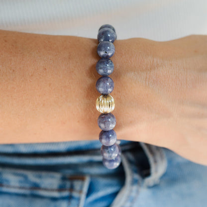 Iolite bracelet with 10mm beads from Earthly Abundance, showcasing polished violet-blue stones on a delicate elastic band.