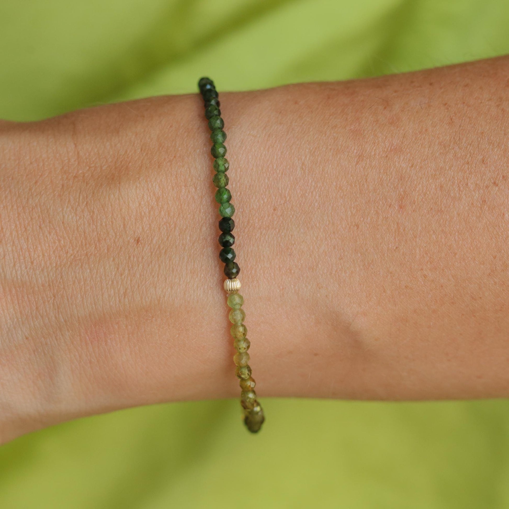 Green tourmaline gemstone set in 14K gold jewelry piece, showcasing vibrant green color and fine craftsmanship.