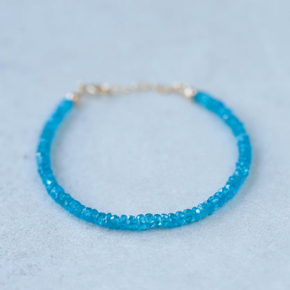 Apatite bracelet with 14K gold clasp, featuring vibrant blue-green apatite gemstones, on a neutral background.