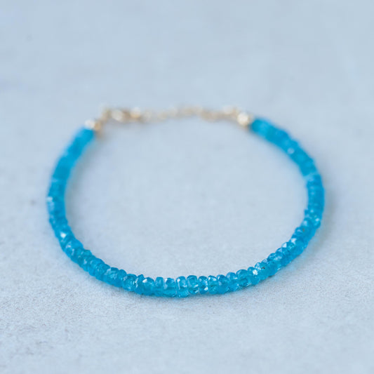 Apatite bracelet with 14K gold clasp, featuring vibrant blue-green apatite gemstones, on a neutral background.