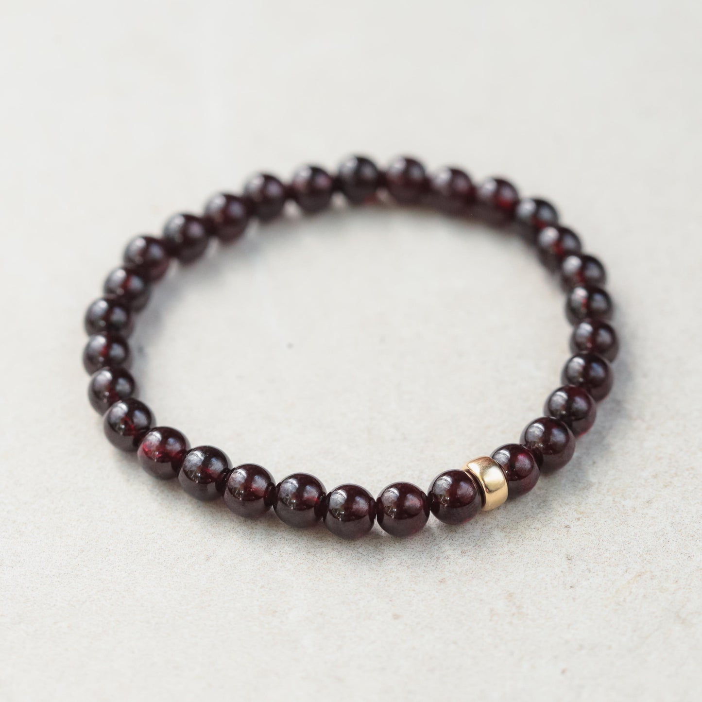 Garnet bracelet with 6mm beads in 14K gold setting, featuring polished deep red garnet stones on a delicate gold chain.