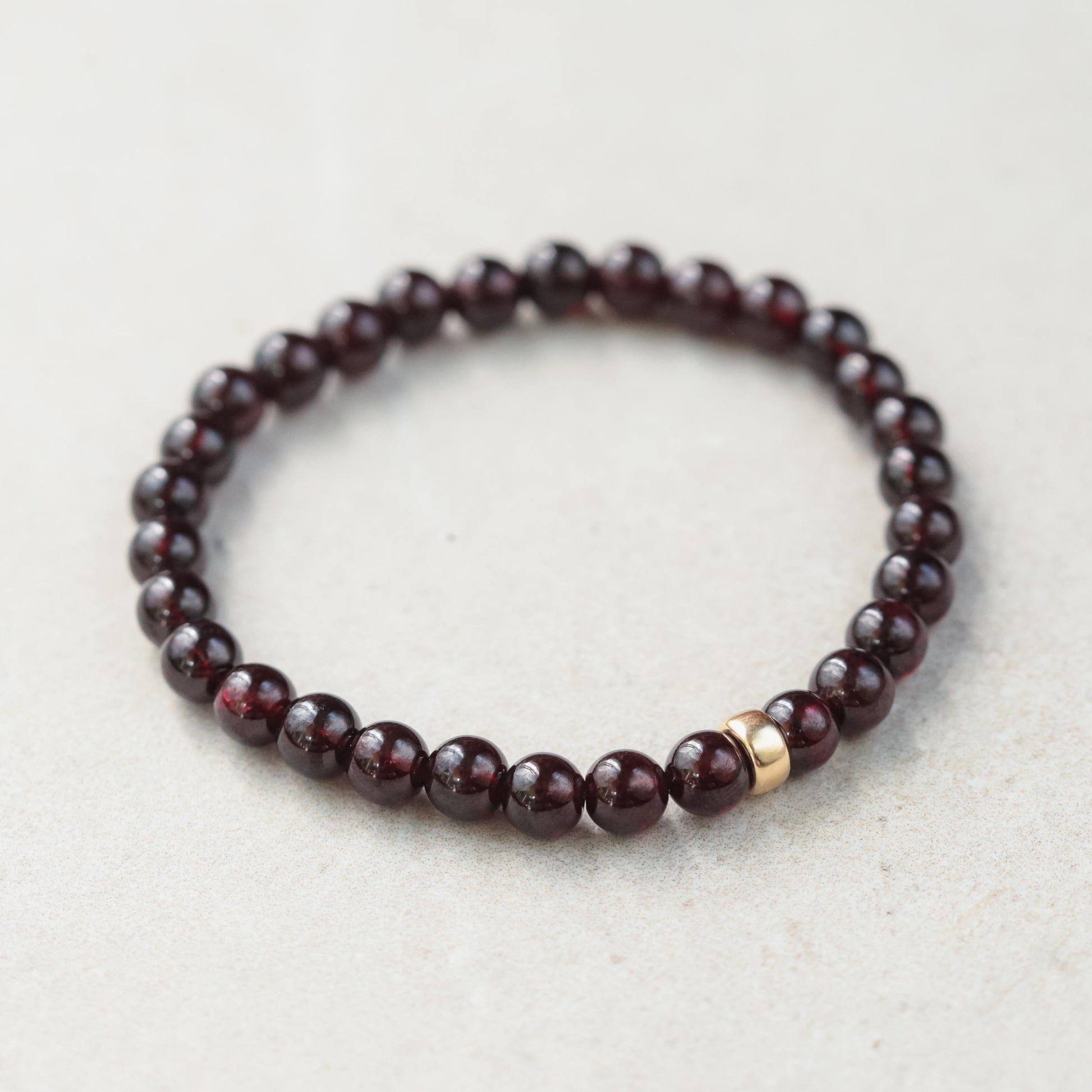Garnet bracelet with 6mm beads in 14K gold setting, featuring polished deep red garnet stones on a delicate gold chain.