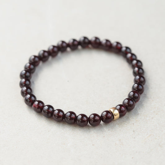 Garnet bracelet with 6mm beads in 14K gold setting, featuring polished deep red garnet stones on a delicate gold chain.