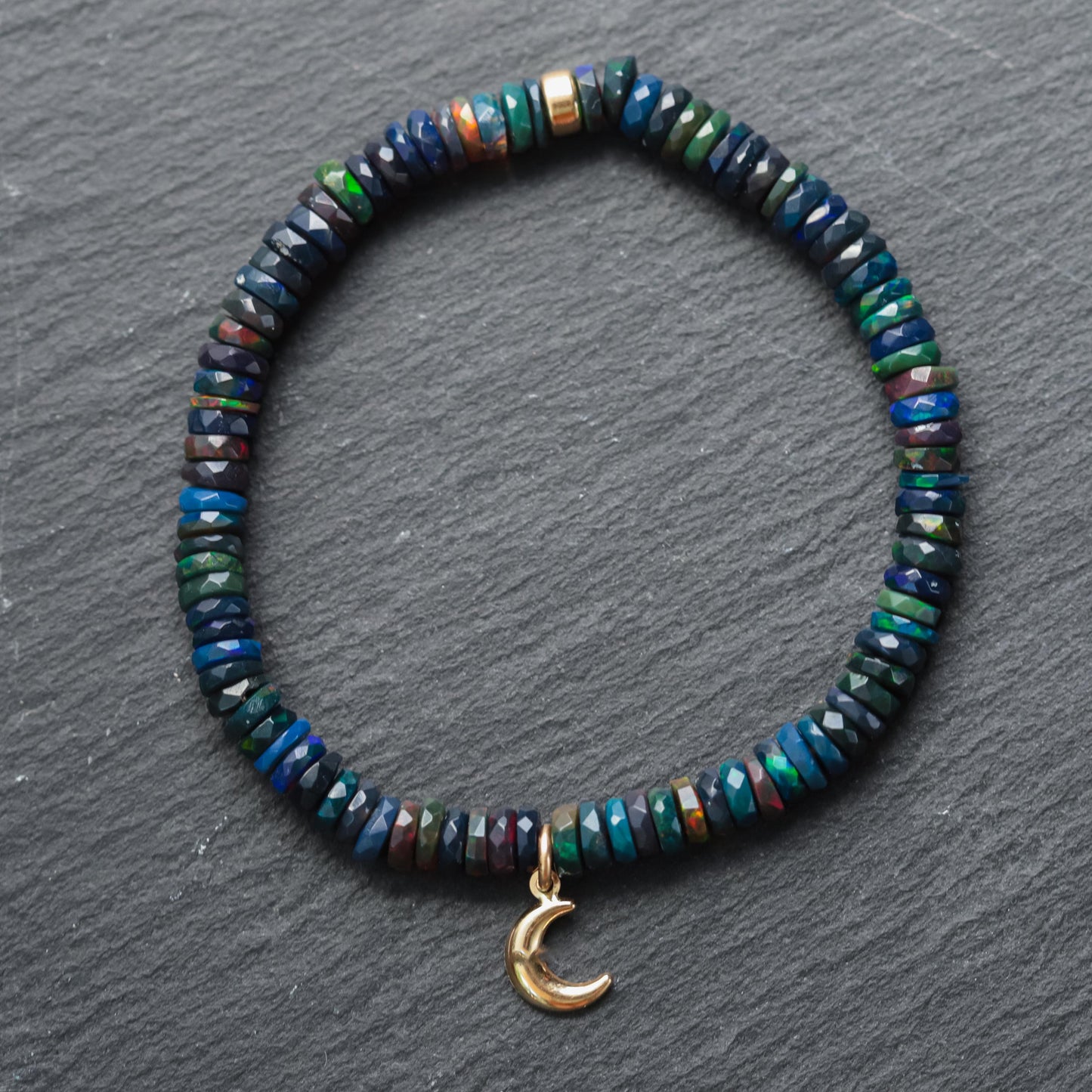 Black Opal Moon bracelet with 14K gold accents from Earthly Abundance, featuring a luminous moon-shaped opal pendant.
