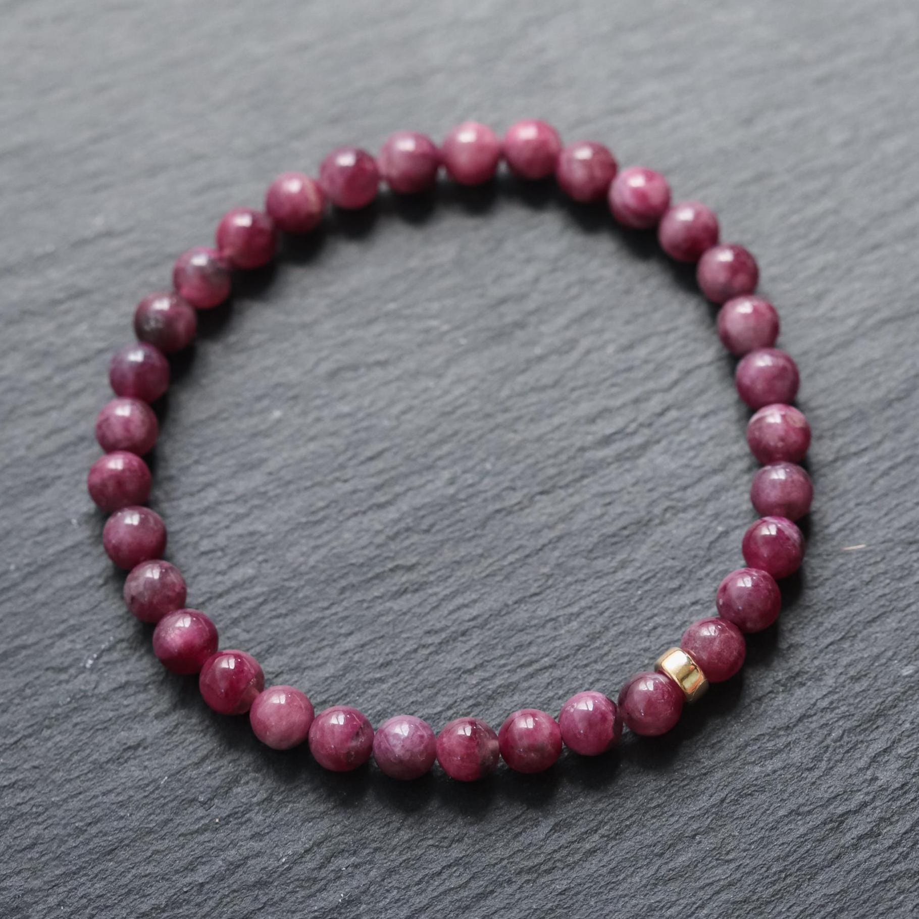 Close-up of a 5mm ruby bracelet in 14K gold from Earthly Abundance, showing vibrant red rubies and gold links.