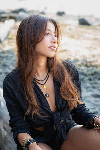 Black tourmaline evil eye necklace with protective charms from Earthly Abundance, featuring a sleek black pendant on a delicate chain.