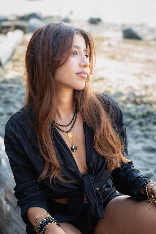 Black tourmaline evil eye necklace with protective charms from Earthly Abundance, featuring a sleek black pendant on a delicate chain.