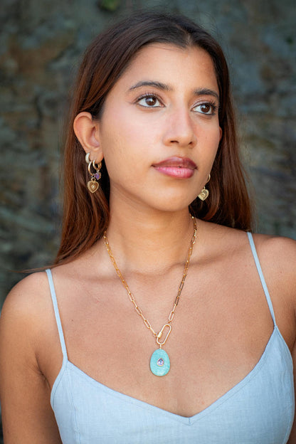 Gold filled paperclip carabiner necklace by Earthly Abundance hanging on a display with a simple background.