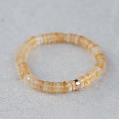 Citrine Heishi bracelet by Earthly Abundance with small orange gemstone beads, stretchy design, on a neutral background.