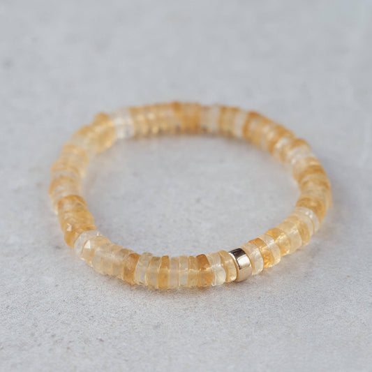 Citrine Heishi bracelet by Earthly Abundance with small orange gemstone beads, stretchy design, on a neutral background.