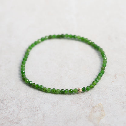 Shimmering chrome diopside gemstone set in a 14K gold jewelry piece, showcasing vibrant green color and intricate craftsmanship.