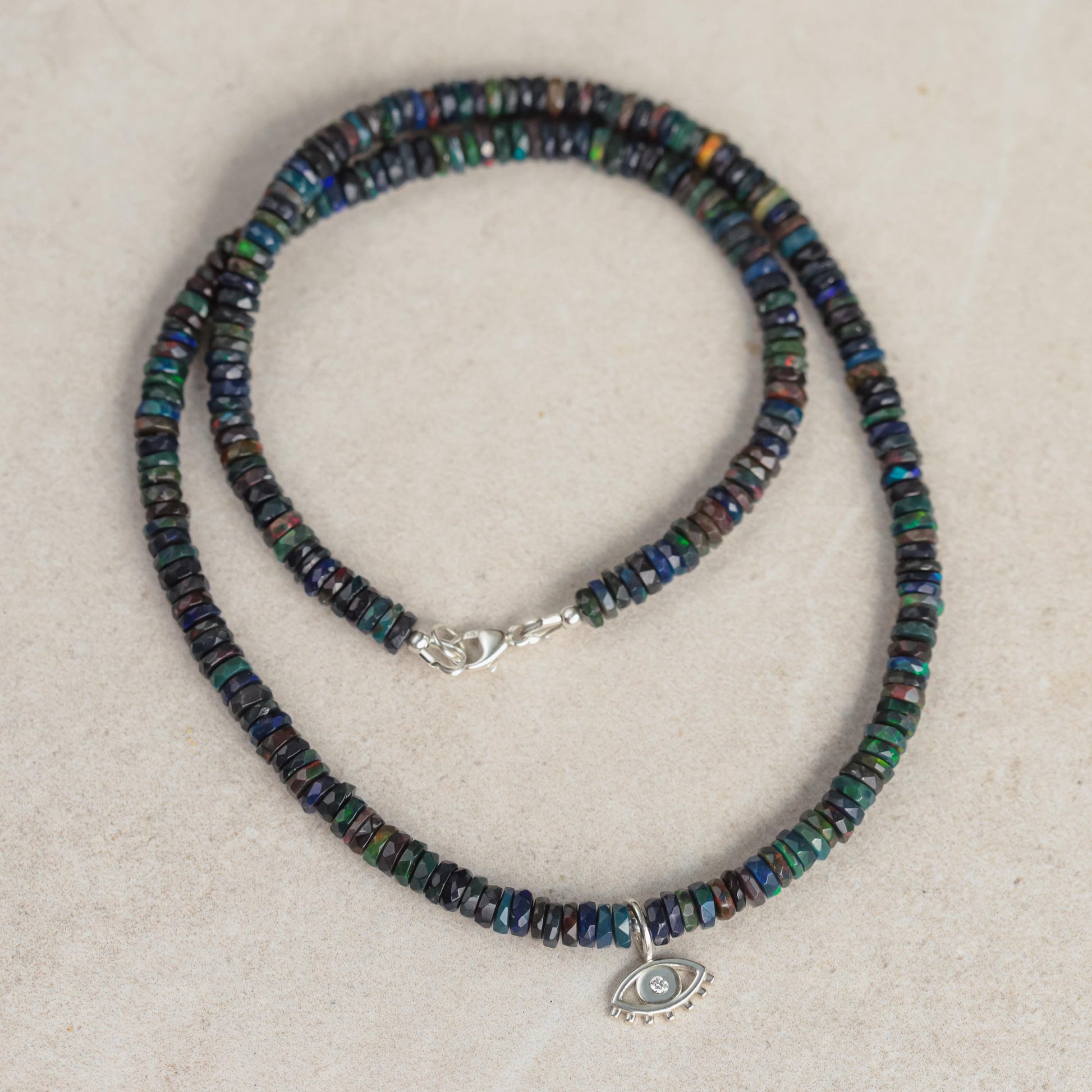 Black Ethiopian Opal and diamond evil eye pendant by Earthly Abundance, featuring intricate design and vibrant gemstone accents.