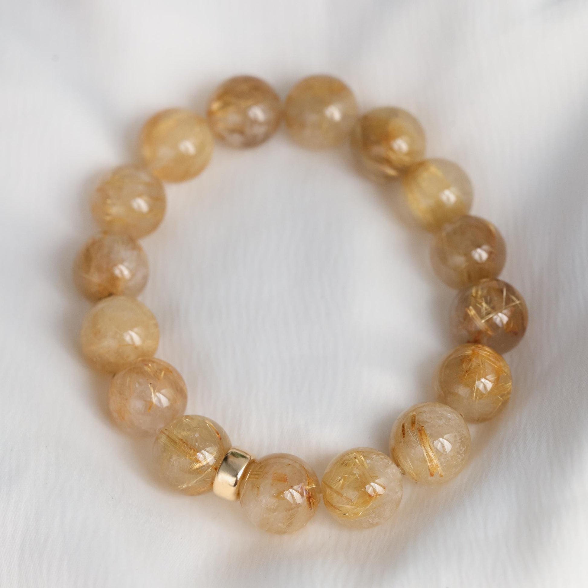 Golden rutilated quartz bracelet with 14K gold accents from Earthly Abundance, featuring polished gemstone beads and intricate gold details.