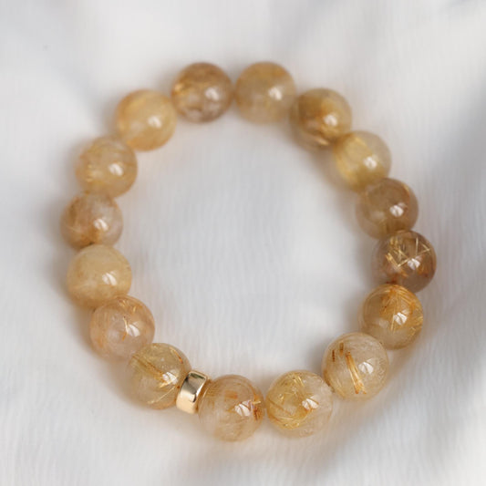 Golden rutilated quartz bracelet with 14K gold accents from Earthly Abundance, featuring polished gemstone beads and intricate gold details.