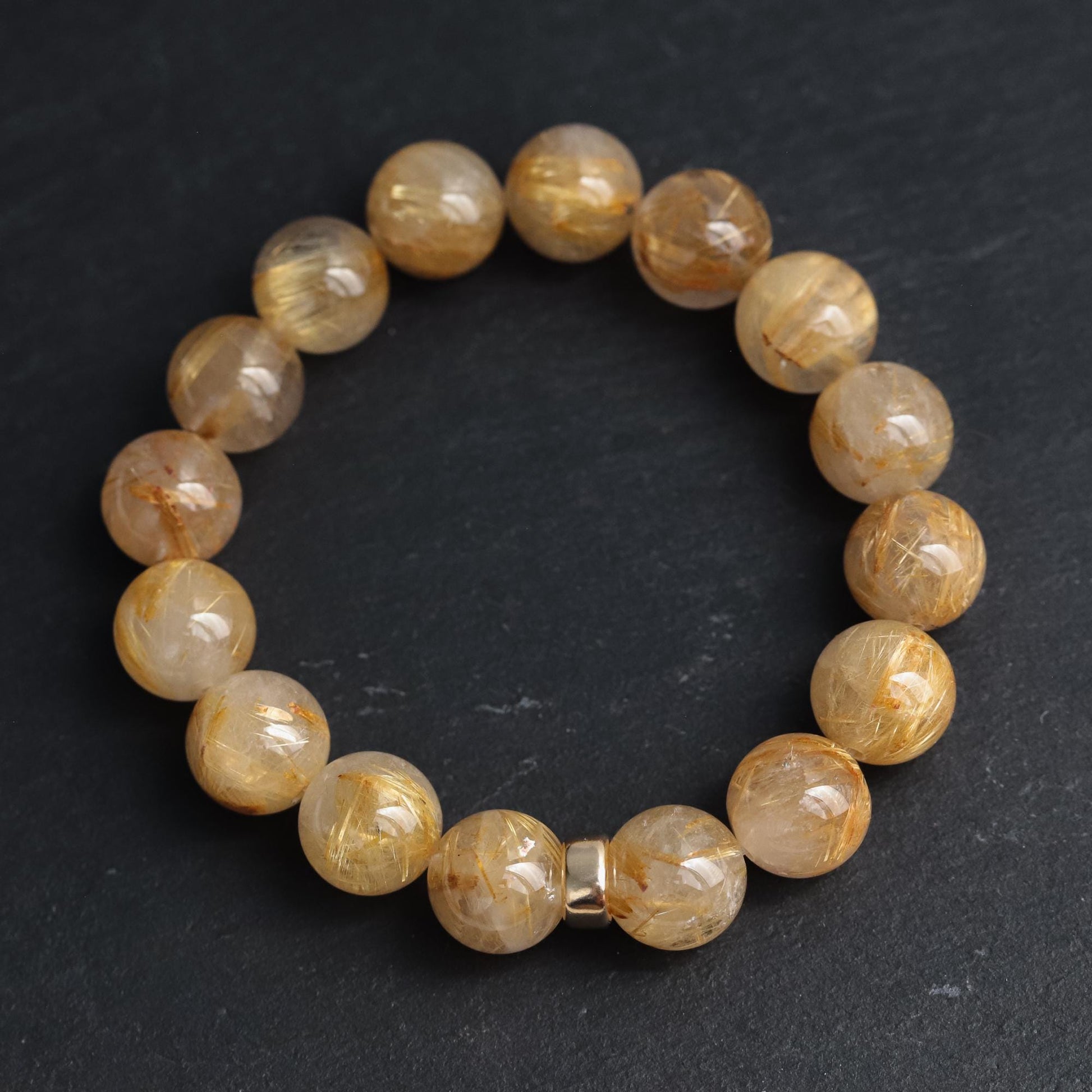 Golden rutilated quartz bracelet with 14K gold accents, featuring polished gemstone beads on a delicate string.