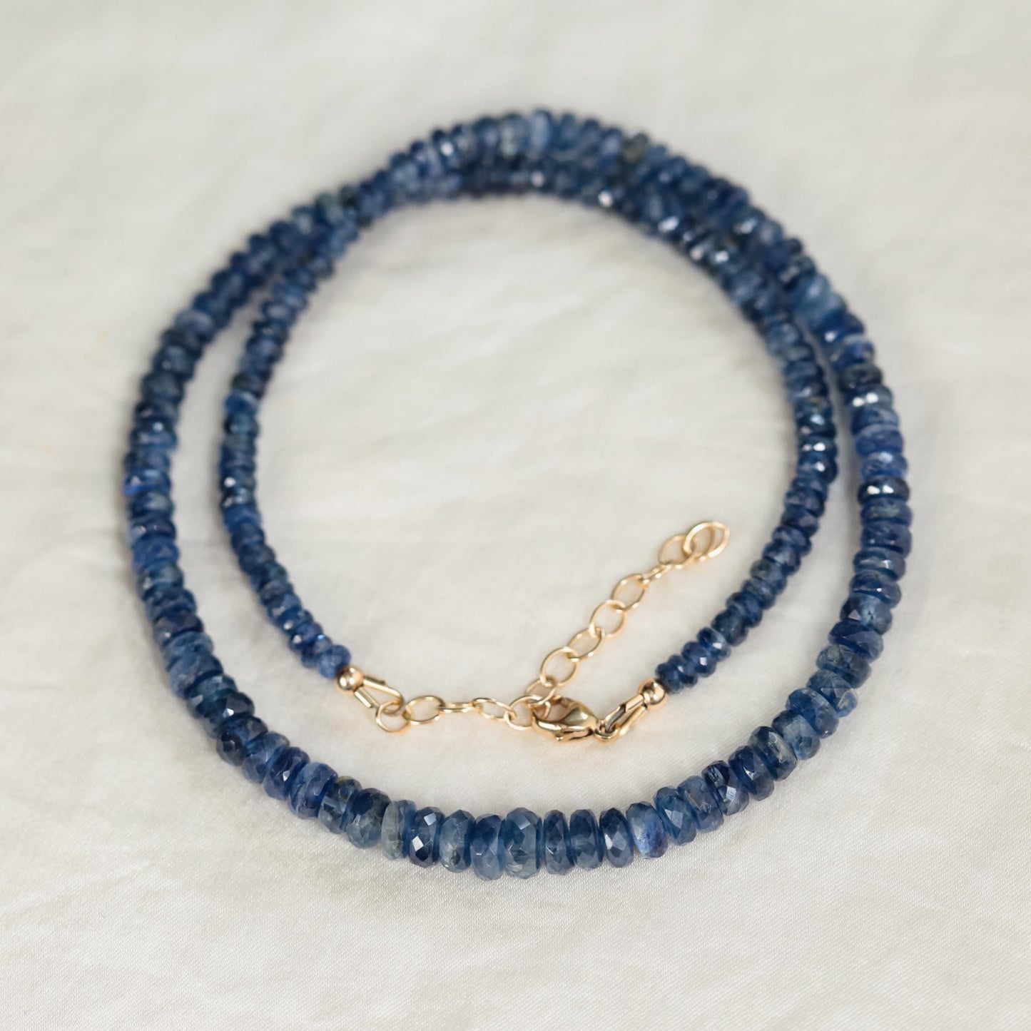 Kyanite necklace with a polished blue gemstone pendant on a silver chain, displayed against a neutral background.
