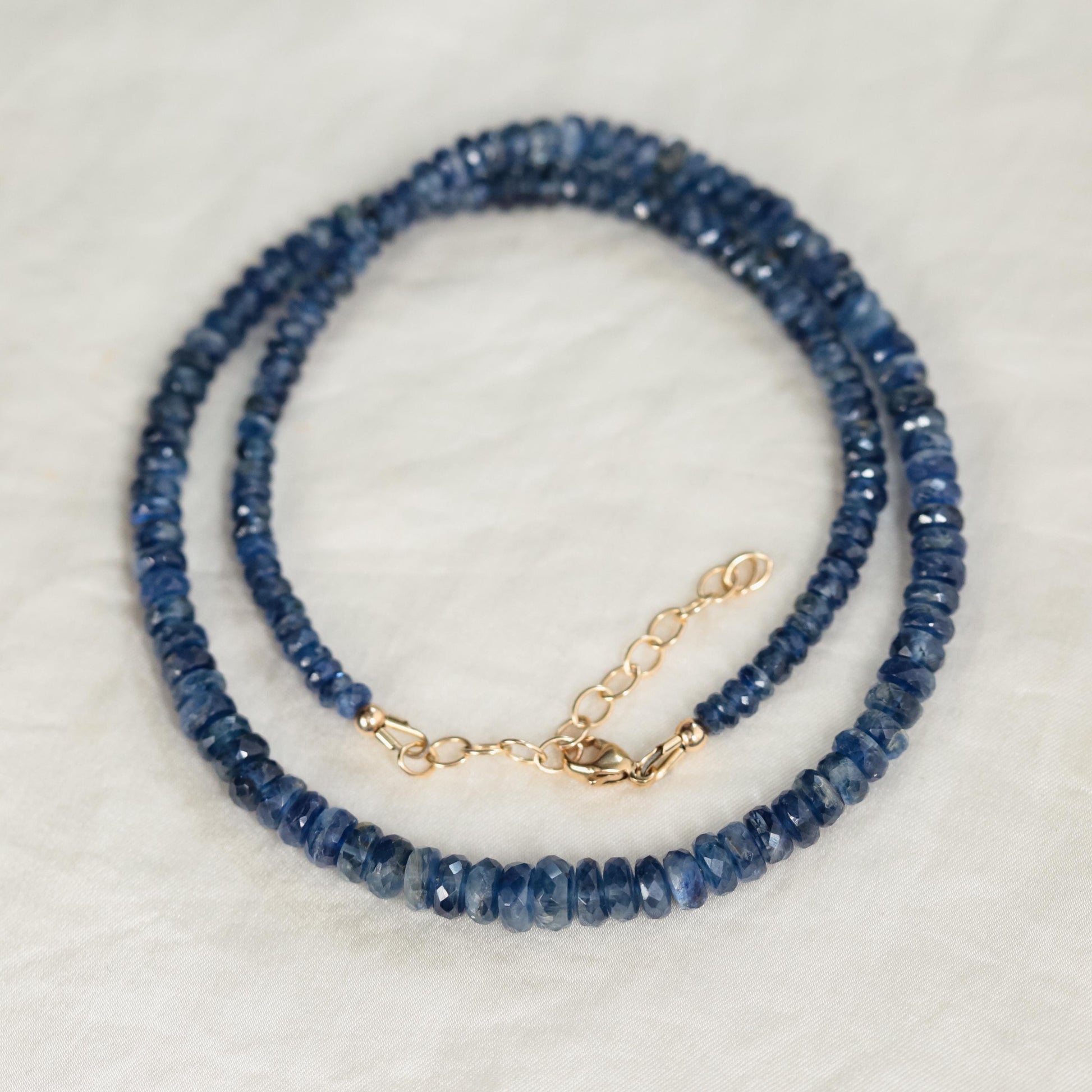 Kyanite necklace with a polished blue gemstone pendant on a silver chain, displayed against a neutral background.