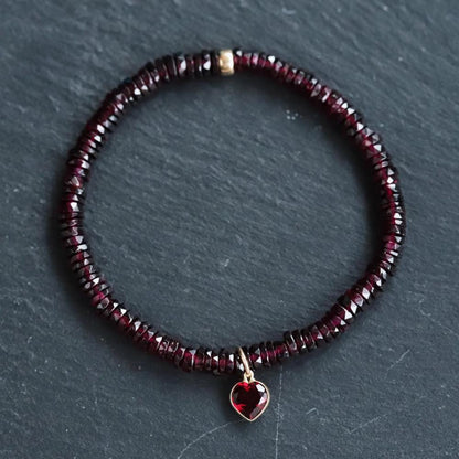 Earthly Abundance garnet heart bracelet featuring polished red gemstone beads and a delicate chain on a neutral background.
