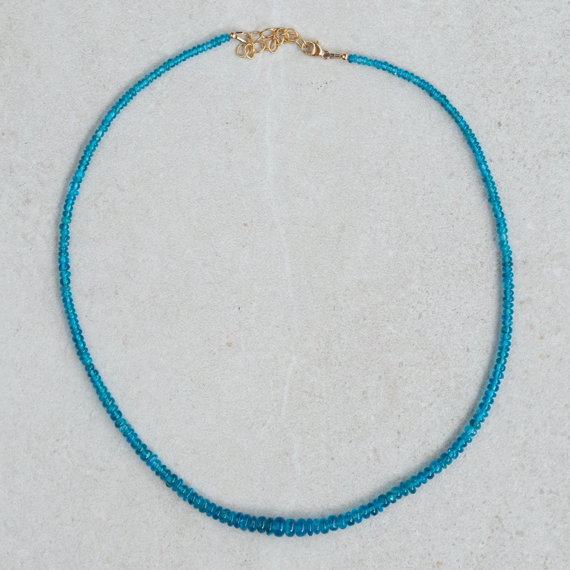 A Gemmy Apatite Necklace featuring a vibrant blue-green apatite pendant on a delicate chain, displayed against a neutral background.