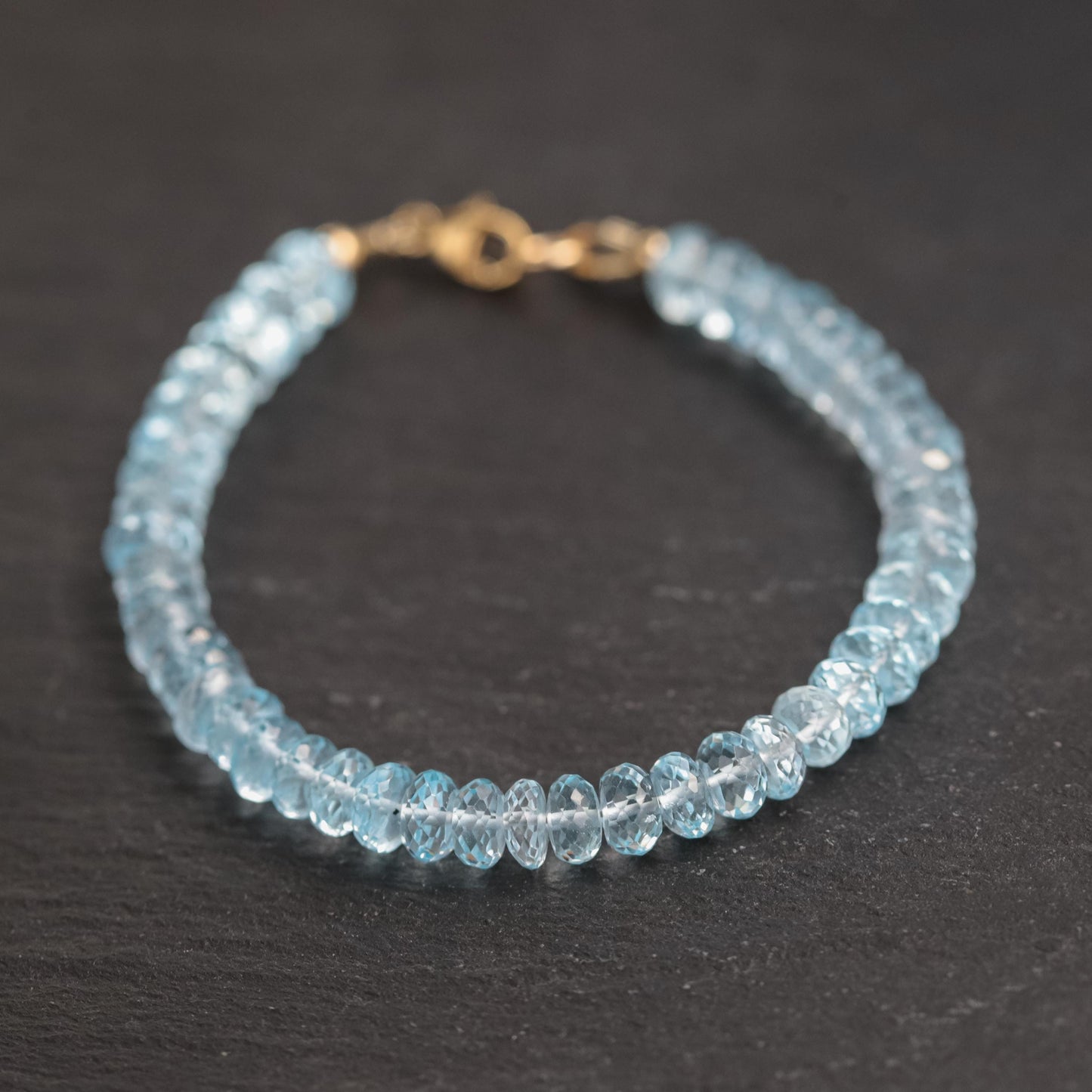 Swiss Blue Topaz bracelet featuring 14K gold setting with sparkling blue gemstones on a delicate chain.