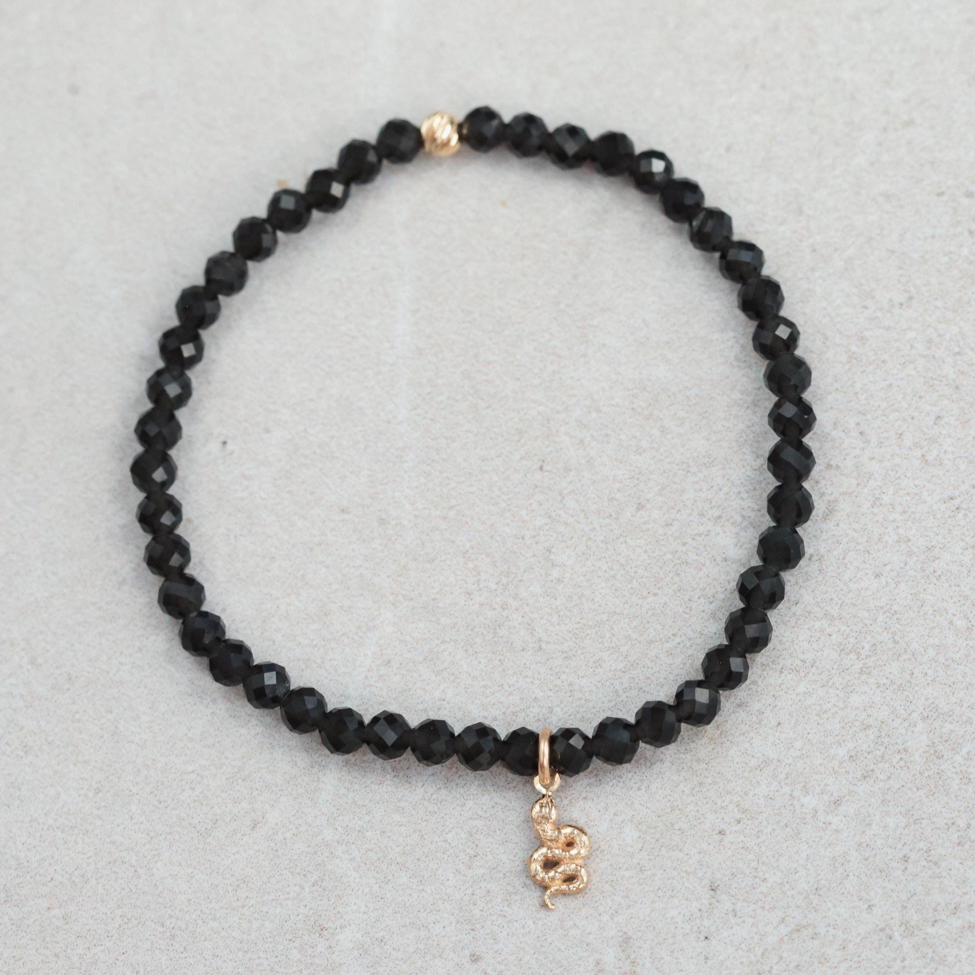 Obsidian snake bracelet crafted with 14K gold from Earthly Abundance, featuring a detailed snake design on a sleek black obsidian band.