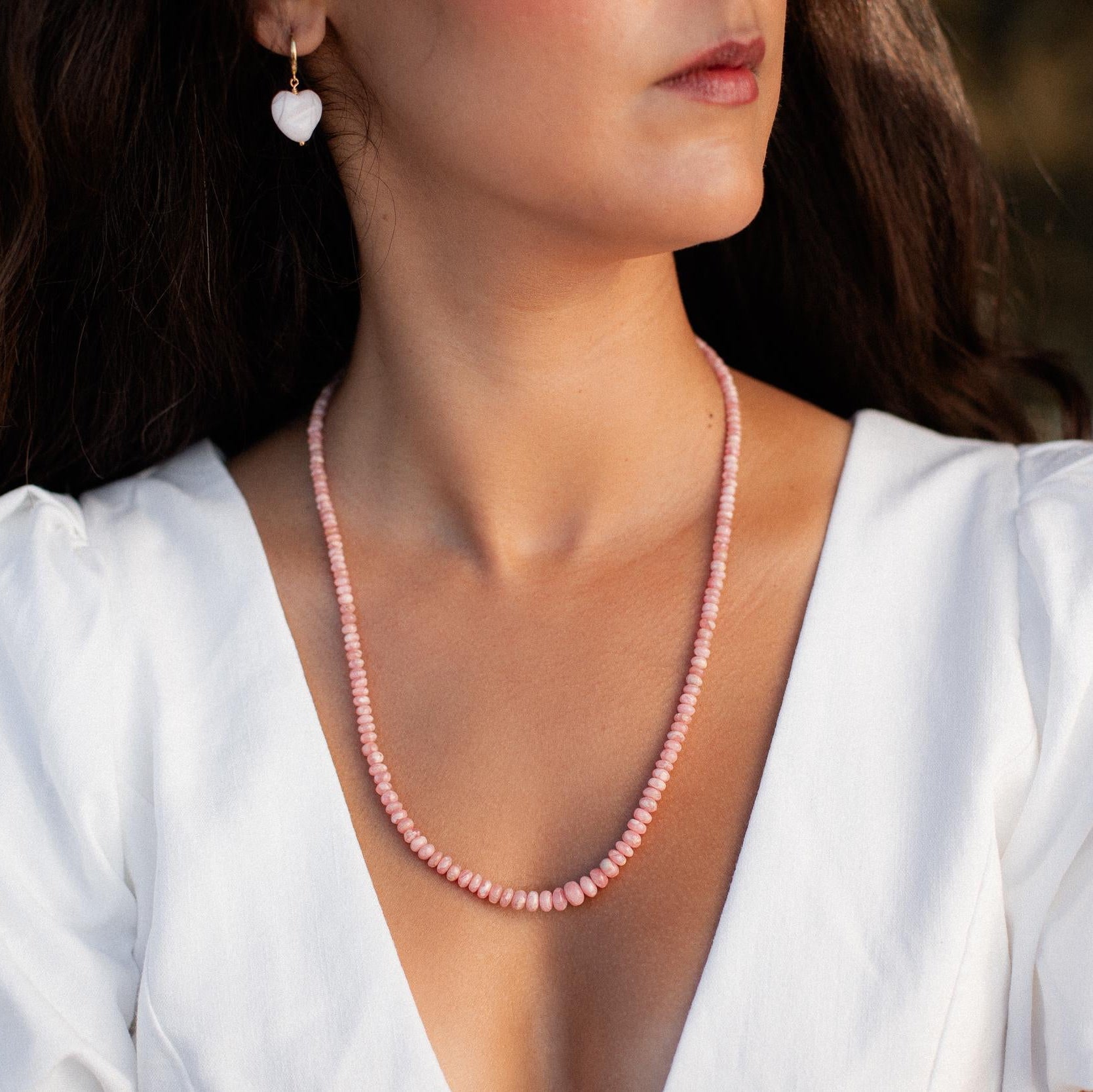 Earthly Abundance Rhodochrosite necklace featuring polished pink gemstone beads and a silver clasp on a white background.