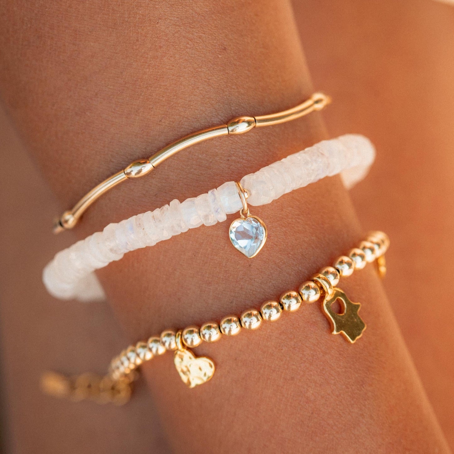 Moonstone bracelet with blue topaz heart charm, 14K gold from Earthly Abundance, featuring polished gemstones and elegant design.