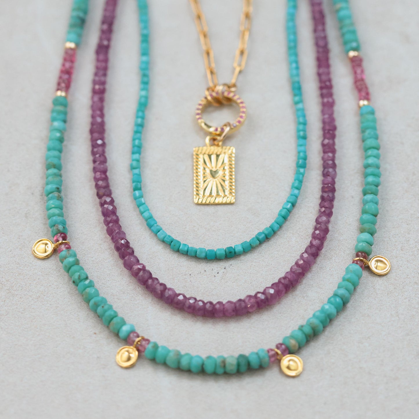 African Ruby necklace featuring vibrant red gemstones on a delicate gold chain, styled with elegant jewelry.