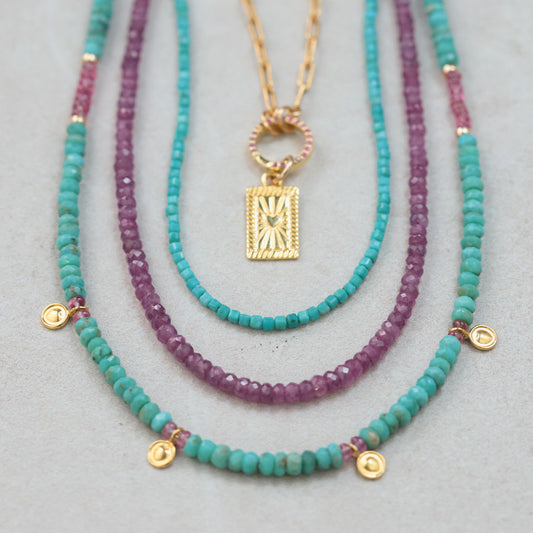 African Ruby necklace featuring vibrant red gemstones on a delicate gold chain, styled with elegant jewelry.