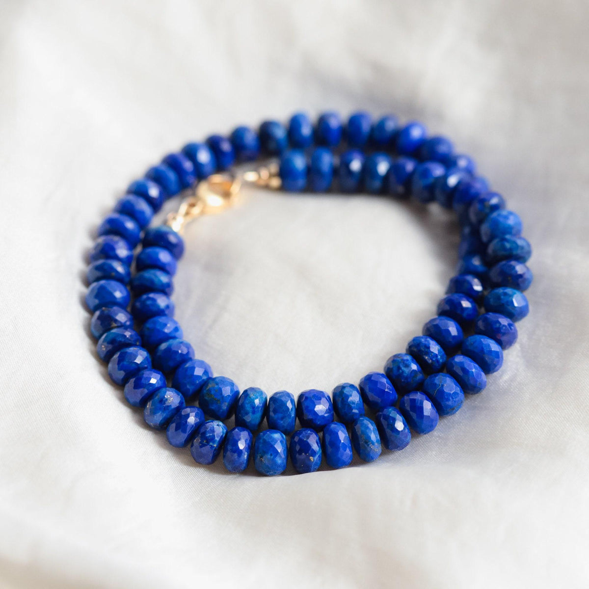 Lapis lazuli faceted rondel necklace with deep blue, gold-tinged stones on a delicate silver chain.