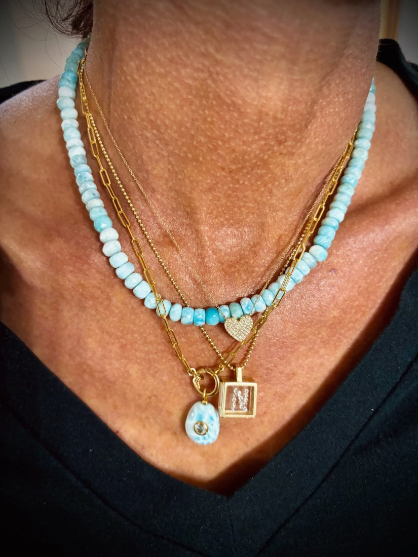 Customer wearing layered larimar necklaces and gold chains