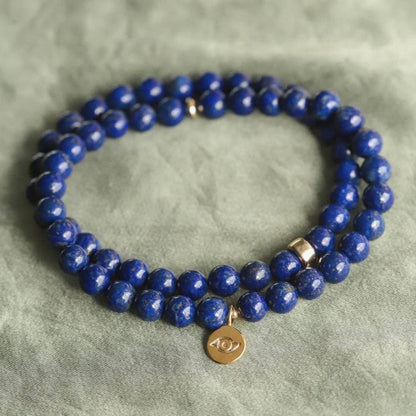 Lapis Lazuli bracelet with polished blue stones and gold accents from Earthly Abundance Jewelry displayed on a neutral background.