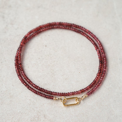 Garnet carabiner necklace by Earthly Abundance featuring a polished garnet stone attached to a metal chain.