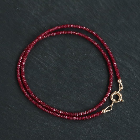 14K Anchor Ruby Necklace by Earthly Abundance featuring a polished gold anchor pendant with a vibrant ruby gemstone.